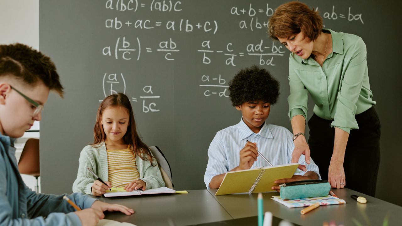 Young students learning maths with teacher in classroom.
