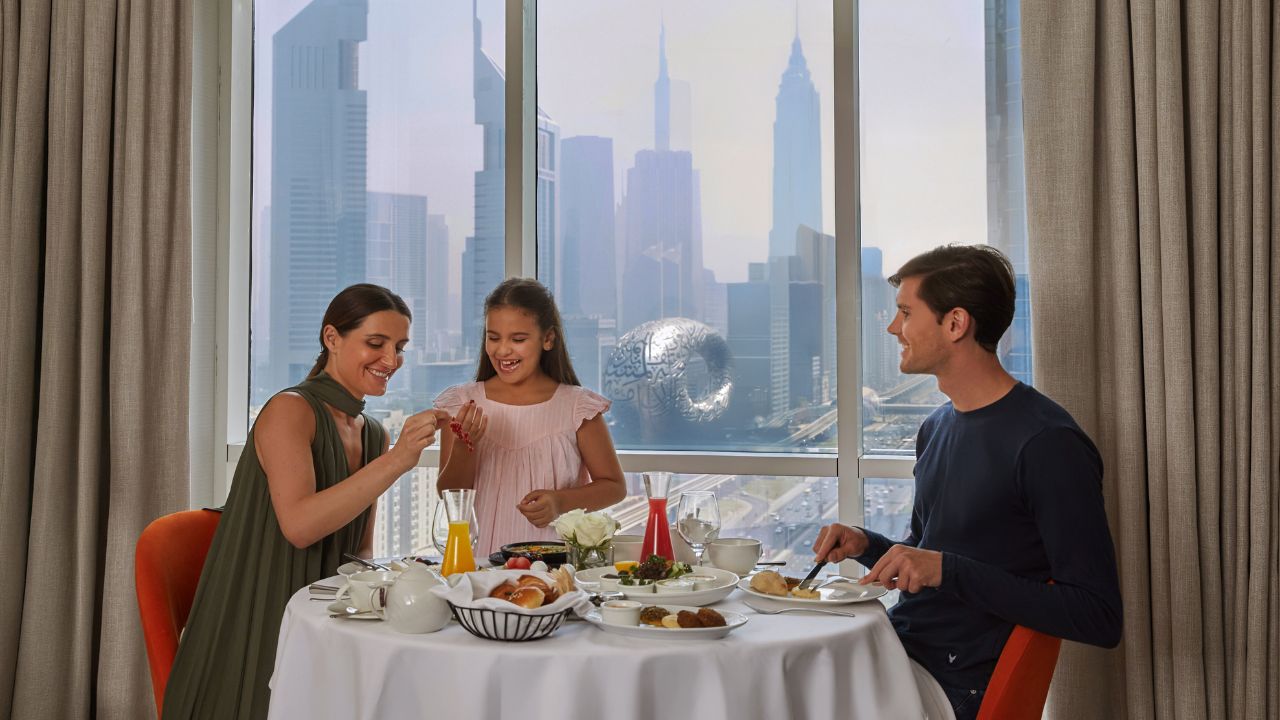 Easter family brunch with kids enjoying a festive meal in Dubai skyline backdrop.