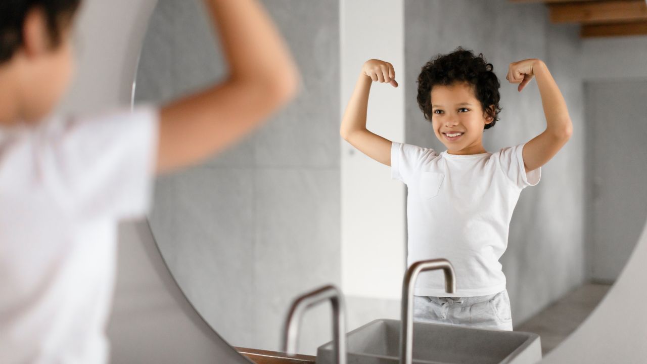 child looking in the mirror flexing