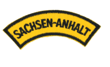 Sachsen-Anhalt Abzeichen, Schwarzer Text auf Gelbem Hintergrund, Nahaufnahme, Erinnerung an regionale Zugehörigkeit.