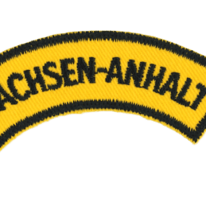 Sachsen-Anhalt Abzeichen, Schwarzer Text auf Gelbem Hintergrund, Nahaufnahme, Erinnerung an regionale Zugehörigkeit.