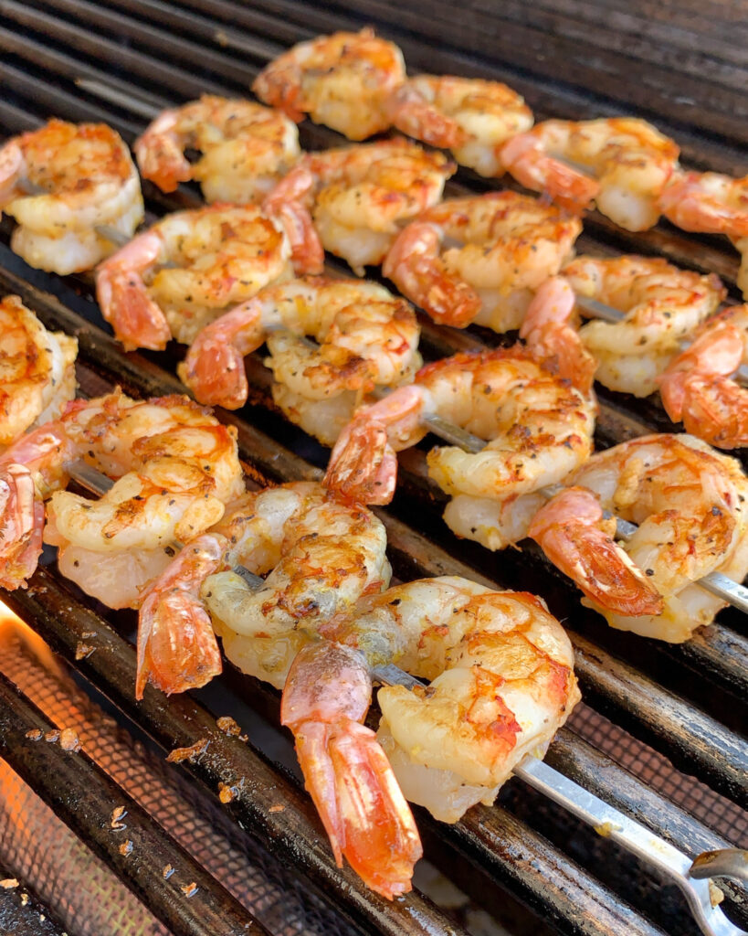 Four skewers of shrimp on the grill.