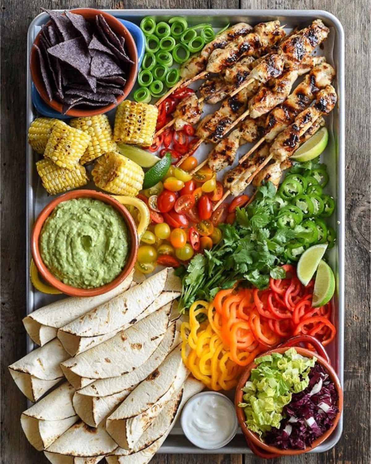 grilled chicken skewers, tortillas, peppers, jalapeños, corn, cucumber and tortilla chips.
