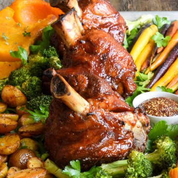 Three sticky BBQ pork hocks served with a variety of roasted veggies.