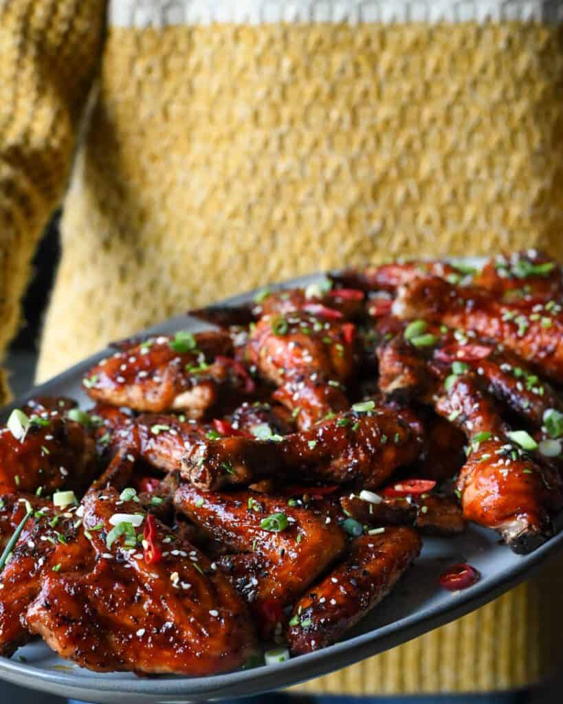 Someone holding a platter filled with sticky Korean chicken wings
