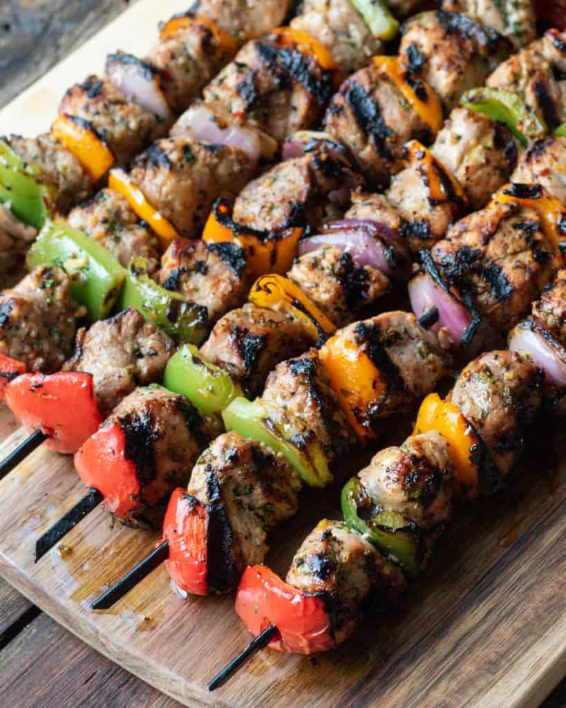 Rows of pork tenderloin and vegetable skewers.