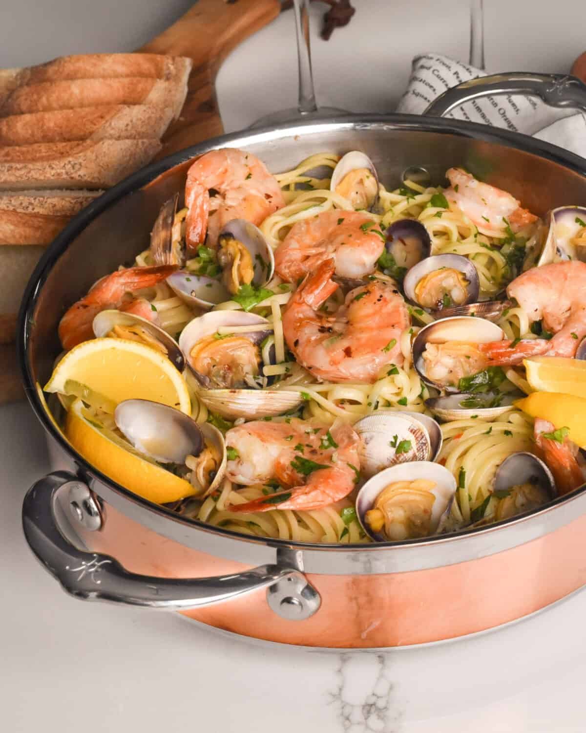A side view of a copper pot filled with clam and shrimp linguine.