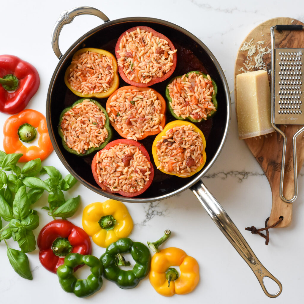 A top down image of a pan with seven Stuffed Peppers in Tomato Sauce