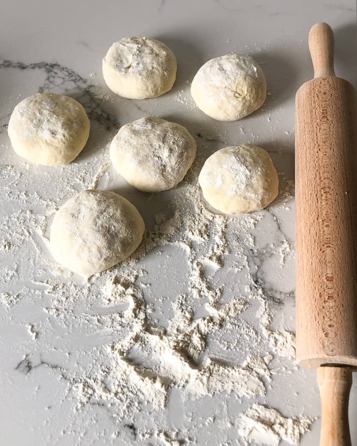 Dough portioned into a balls and sprinkled with flour.