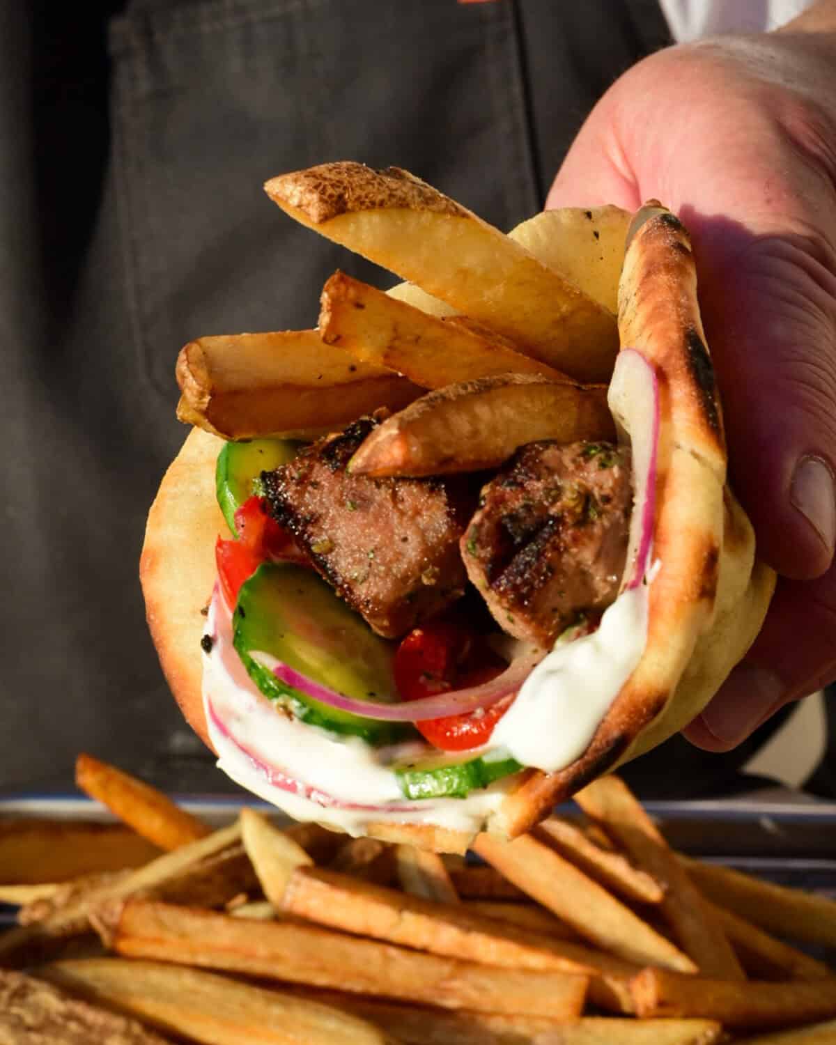 A pork souvlaki pita with fries, veggies and tzatiki.