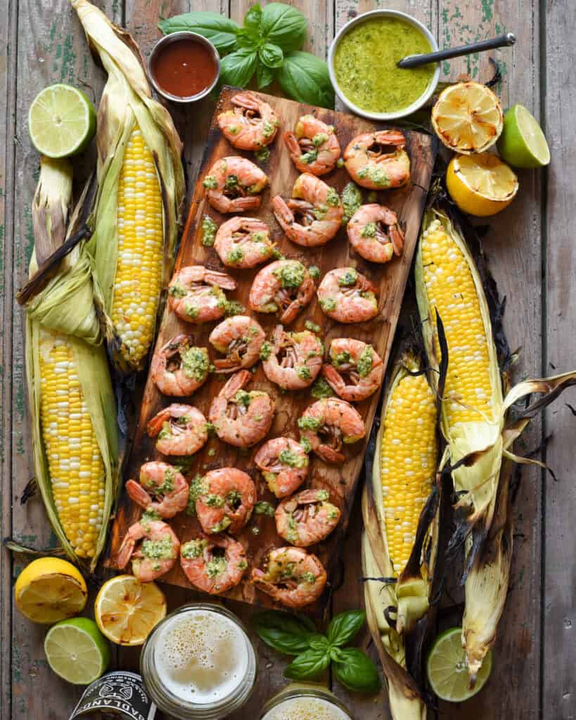 Shrimp cooked on a cedar plank served with dip and corn on the cob.