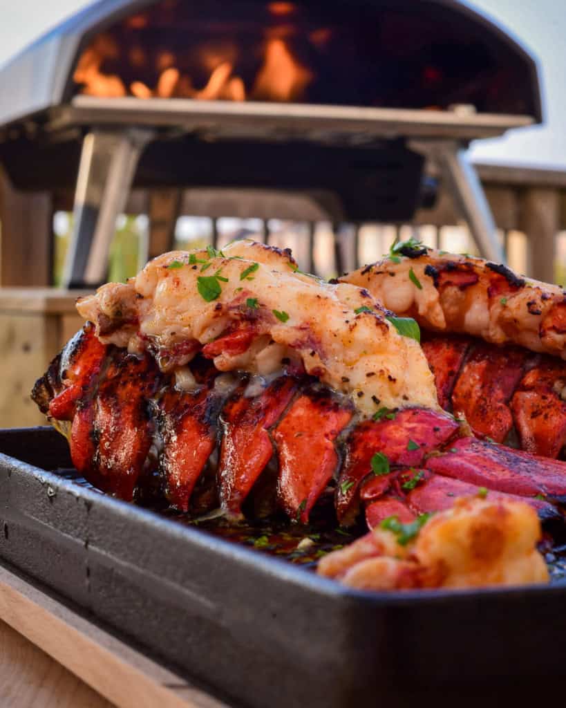 Two lobster tails on a cast iron skillet in the Ooni Koda 16 oven.