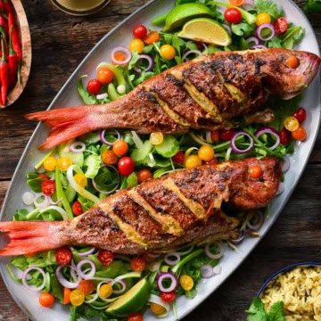 Two Pan Fried Wild Vermilion Snapper fish with Green Curry. Served over a bed of arugula salad with tomatoes.