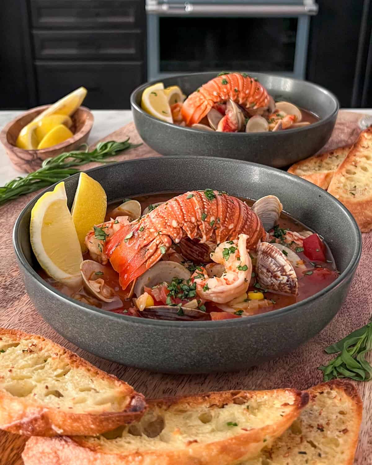 Two bowls of cioppino with rock lobster tails.