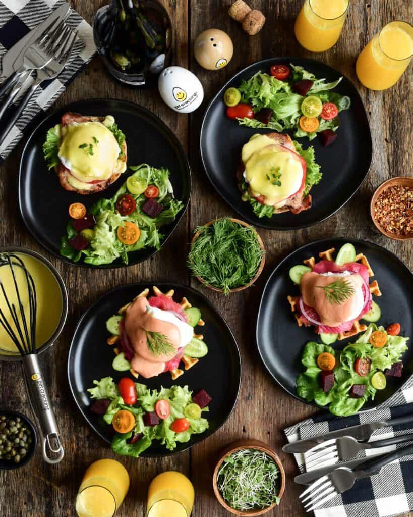 Four plates with eggs benedict, two with a beet hollandaise and two regular hollandaise.