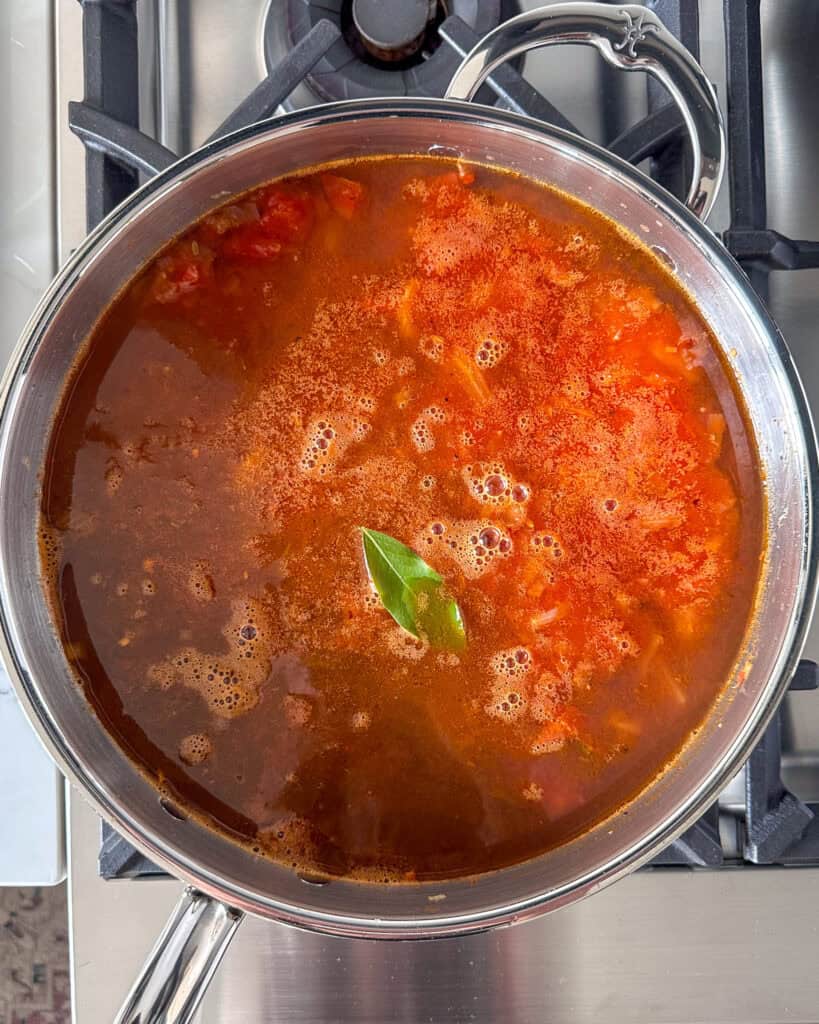 Add the stock, tomatoes and bay leaf and bring to a boil.
