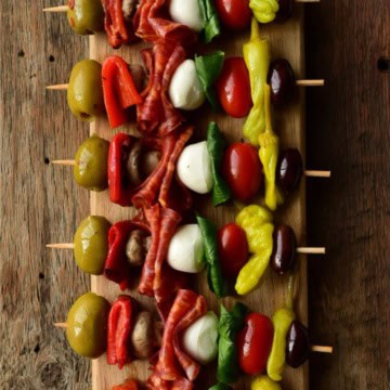 A row of colourful antipasto skewers.