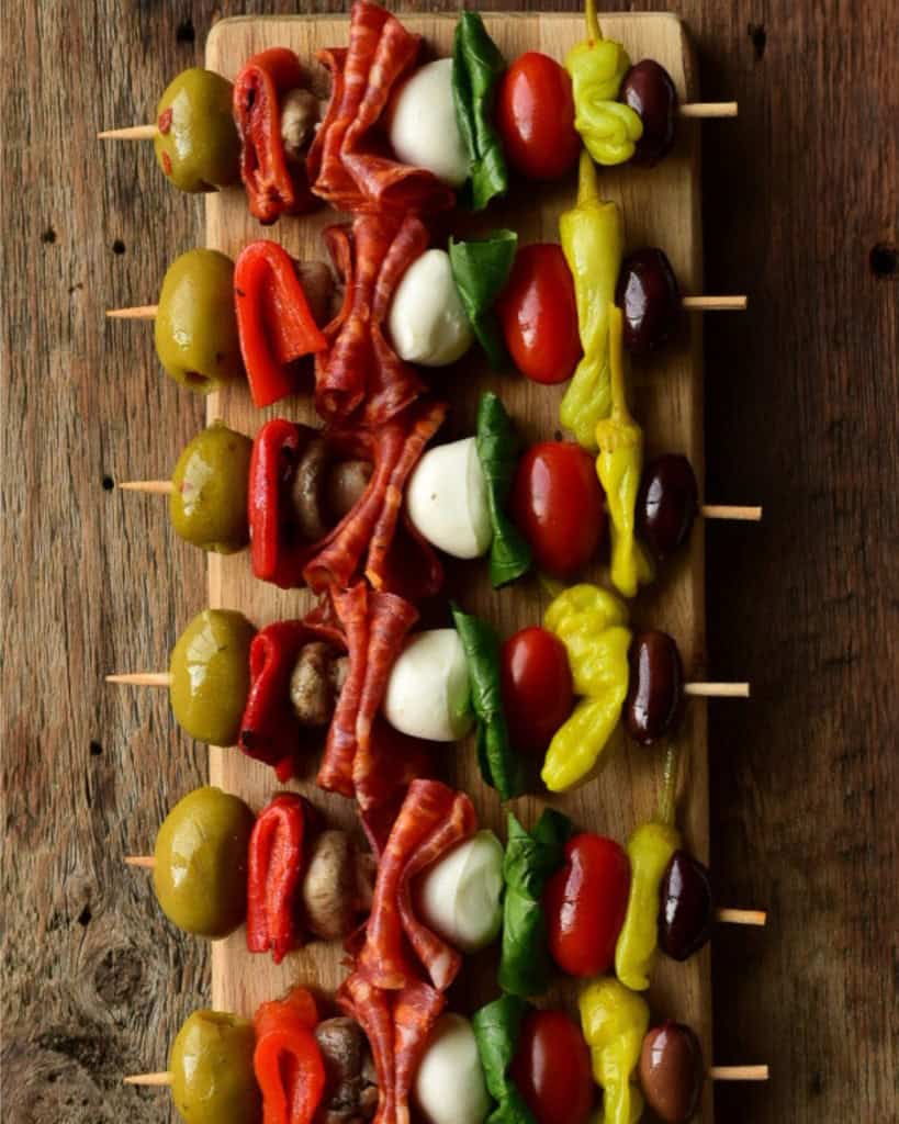 A row of colourful antipasto skewers.
