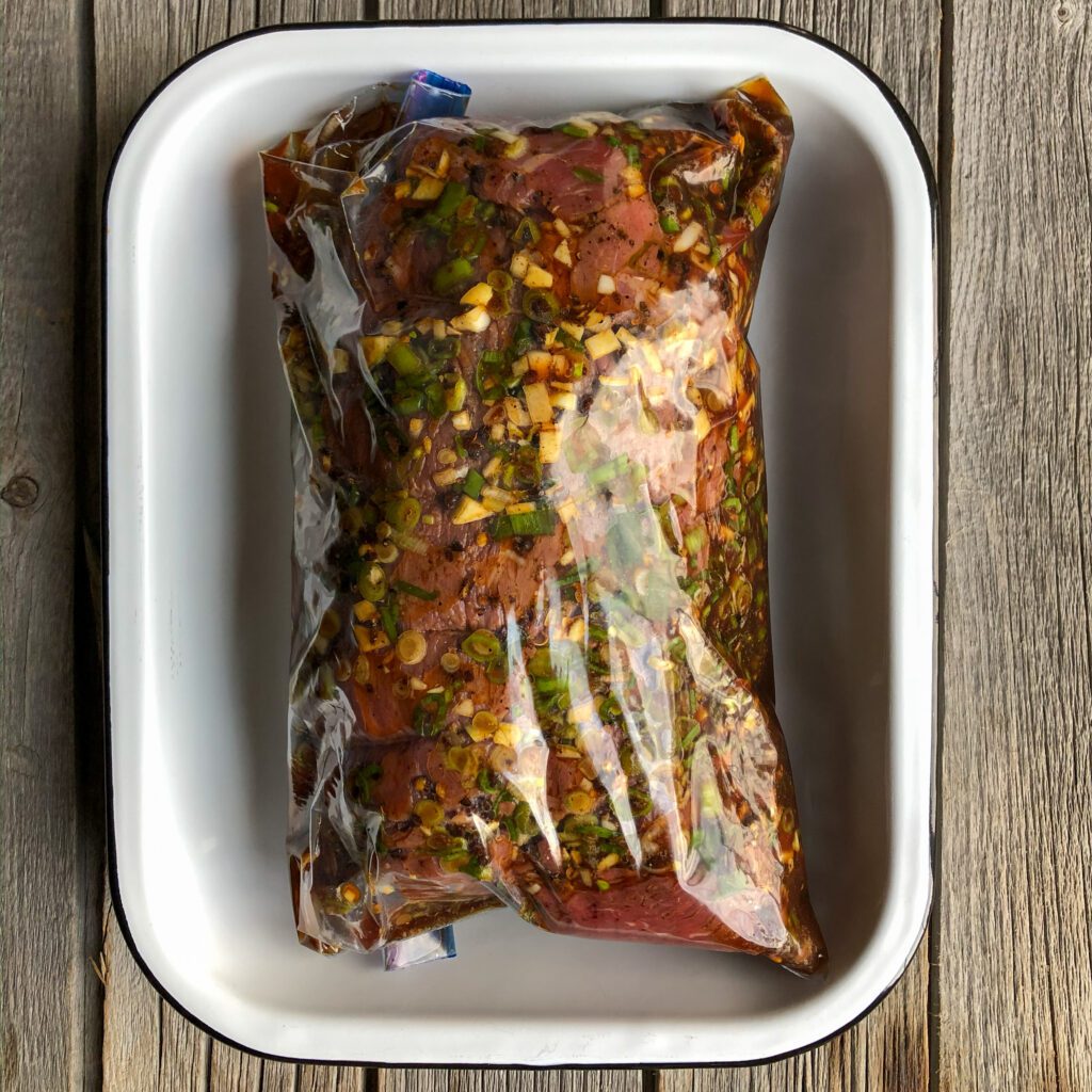 An image of a beef roast in a sealed bag marinating with a Sichuan marinade.