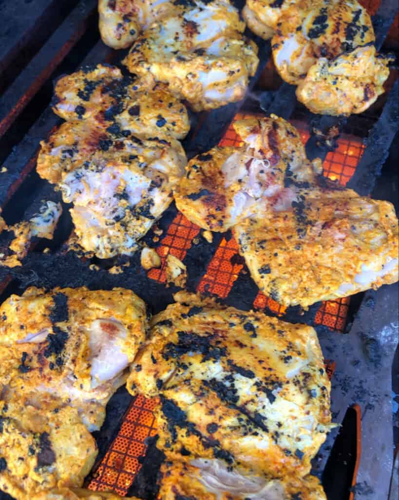 Chicken thighs on the grill with char marks.