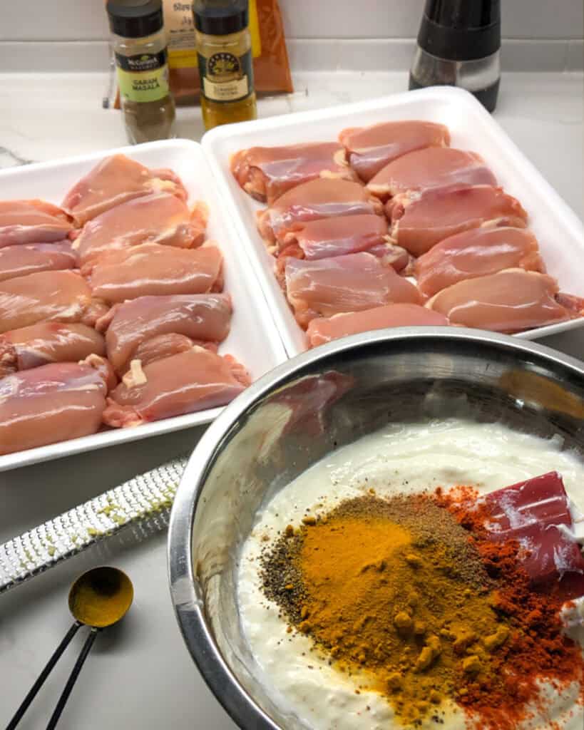 A bowl of chicken tikka marinade ingredients with chicken thighs.
