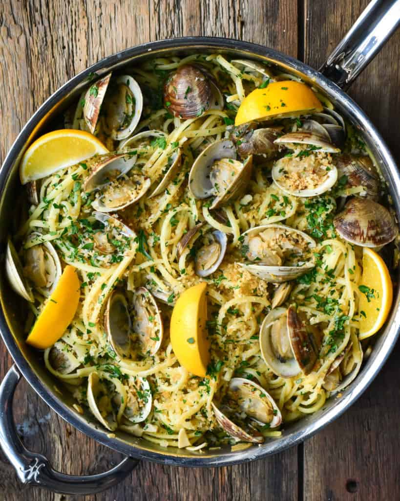 A finished pan of linguine and clams (Linguine alle Vongole) with lemons.