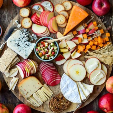 An apple and cheese board with various sliced apples and cheese.