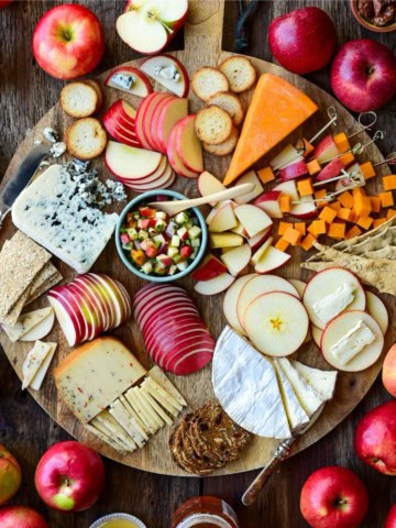 An apple and cheese board with various sliced apples and cheese.