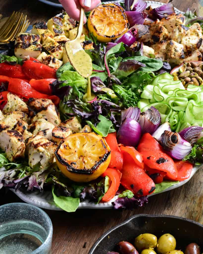 Spoon the salad dressing over the chicken and halloumi salad.