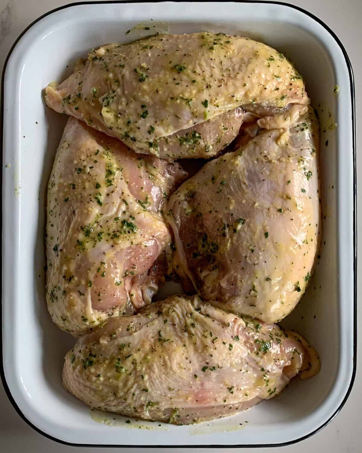 Four chicken breasts marinating in a lemon, oregano garlic sauce.