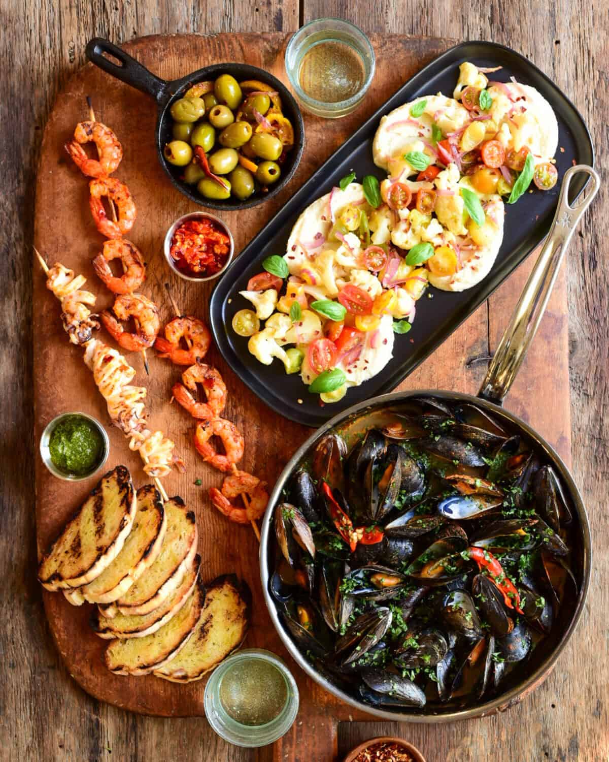 An appetizer board of mussels were served with toast for dipping, warm olives, grilled shrimp, grilled calamari and hummus with griddled veggies.