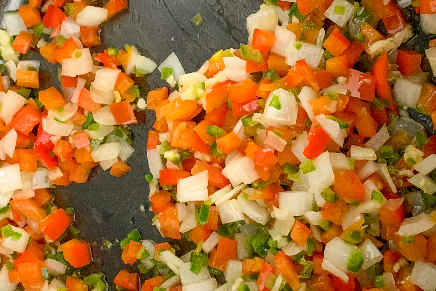 Sauté onions, bell peppers and garlic for a chicken and corn chowder recipe.