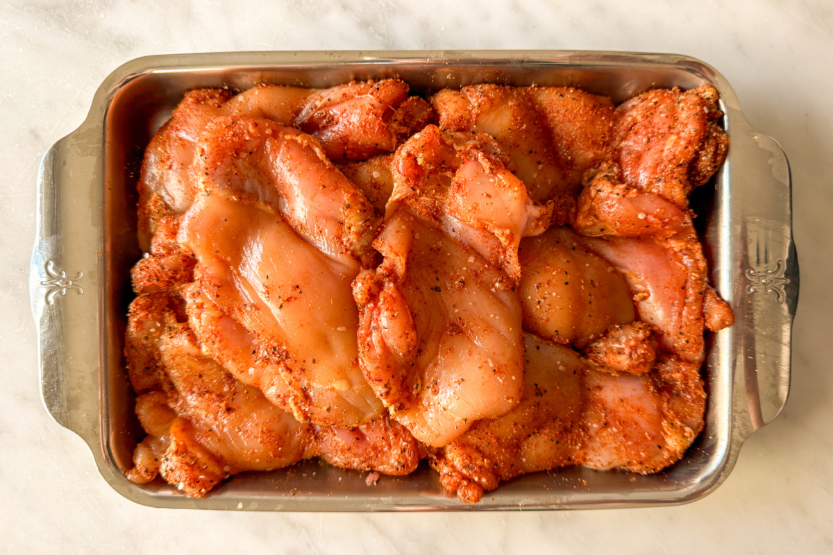 A tray with seasoned chicken thighs for a chicken and corn chowder recipe.