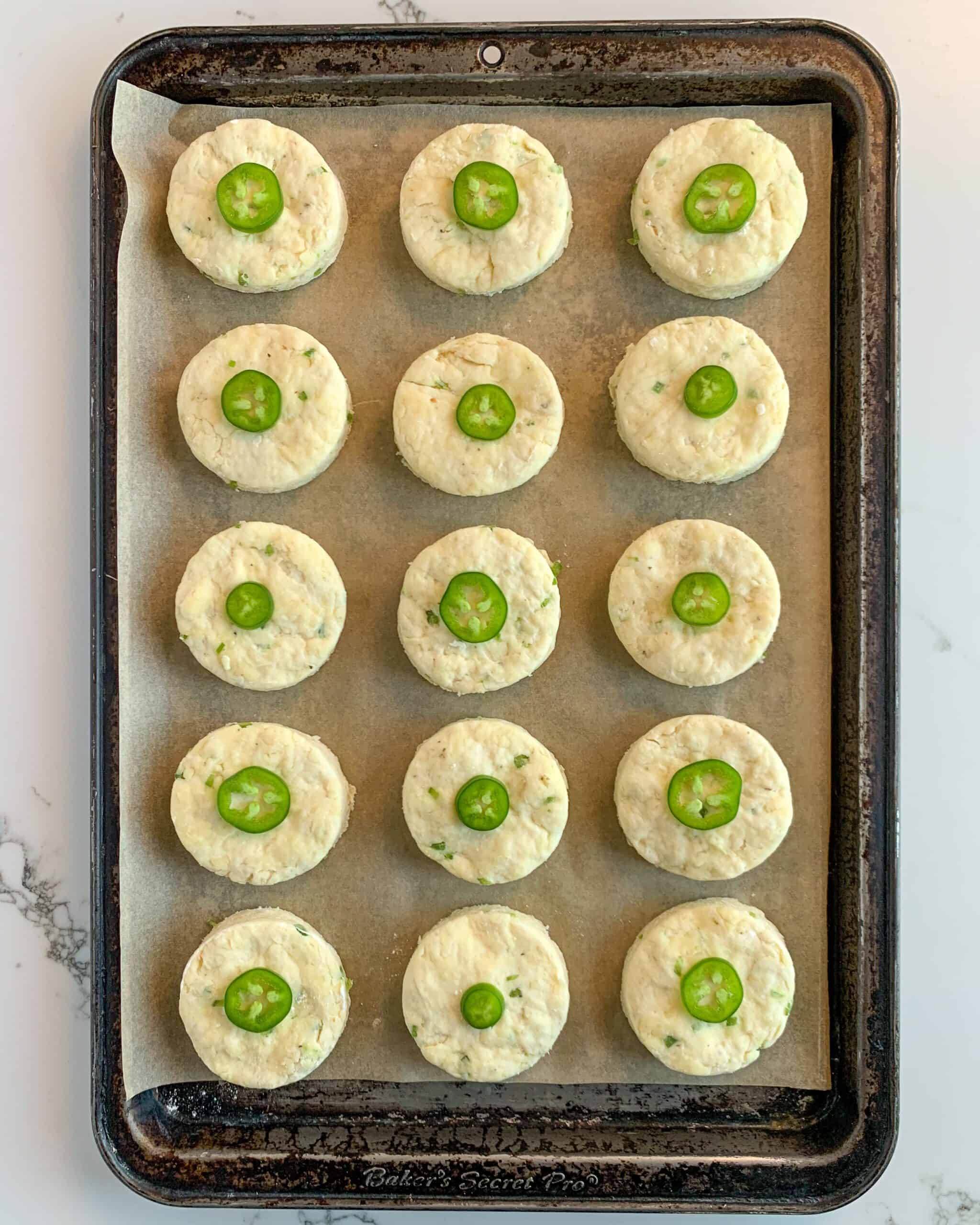 This is an image of the biscuits placed on the baking tray with a jalapeno slice on top