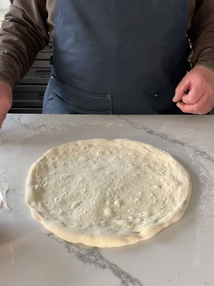 An image of a stretched out pizza dough.