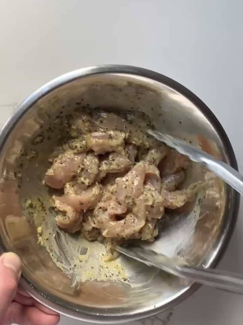 A bowl of marinated chicken strips.