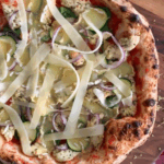 A close up of a Lemon-Rosemary Chicken Pizza with cheese strips.