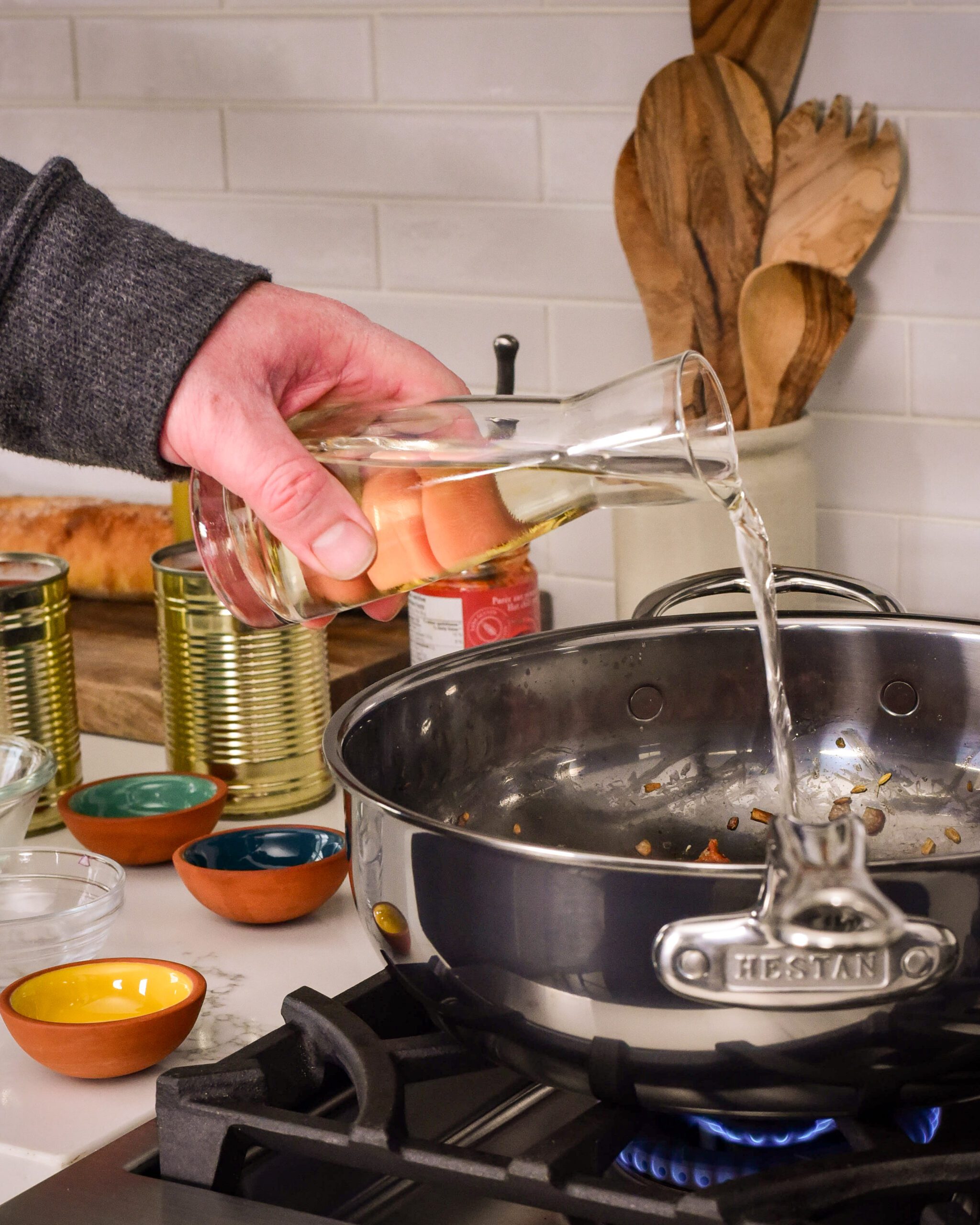 Adding a bottle of white wine into the pot on the stove for mussels in tomato and white wine sauce recipe.