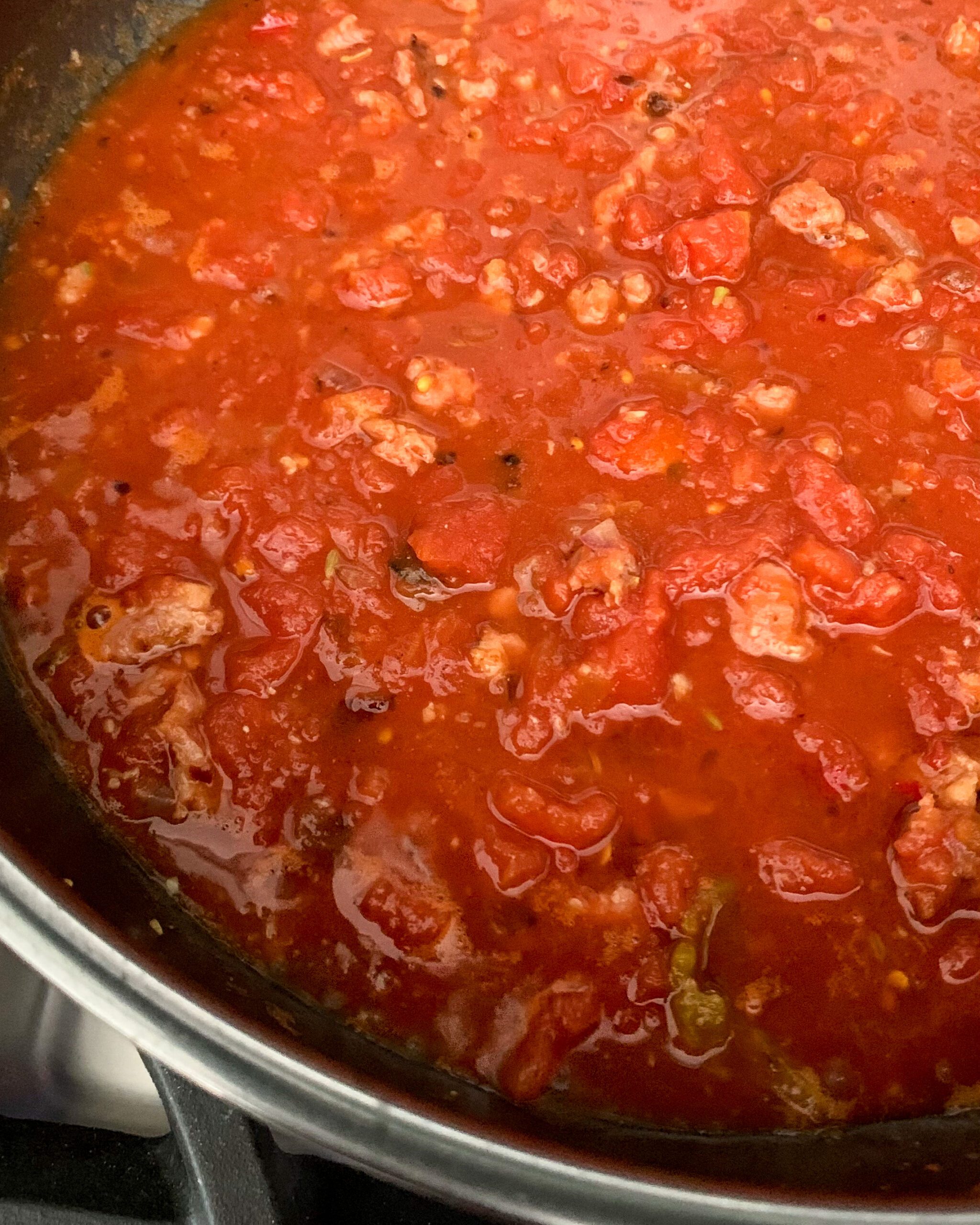 A simmering pot of tomato broth for a mussels and sausage recipe.