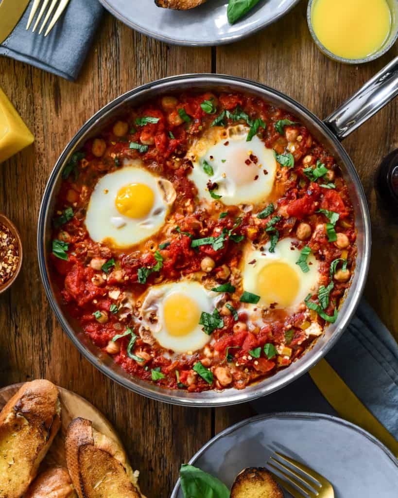 A top down image of a no bake shakshuka with four eggs in a skillet on a table ready to be served.