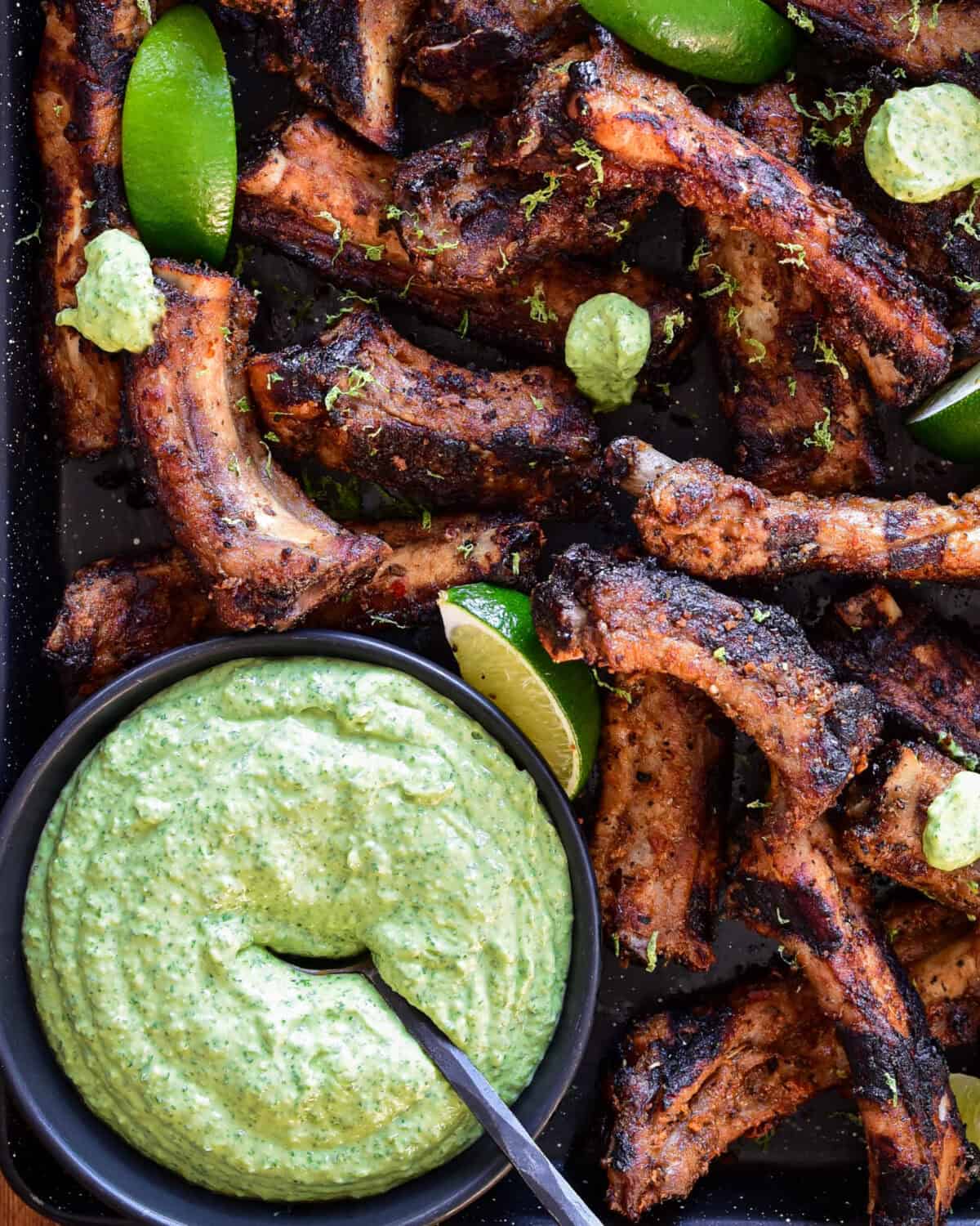 A bowl of Peruvian green sauce with Peruvian marinated ribs.