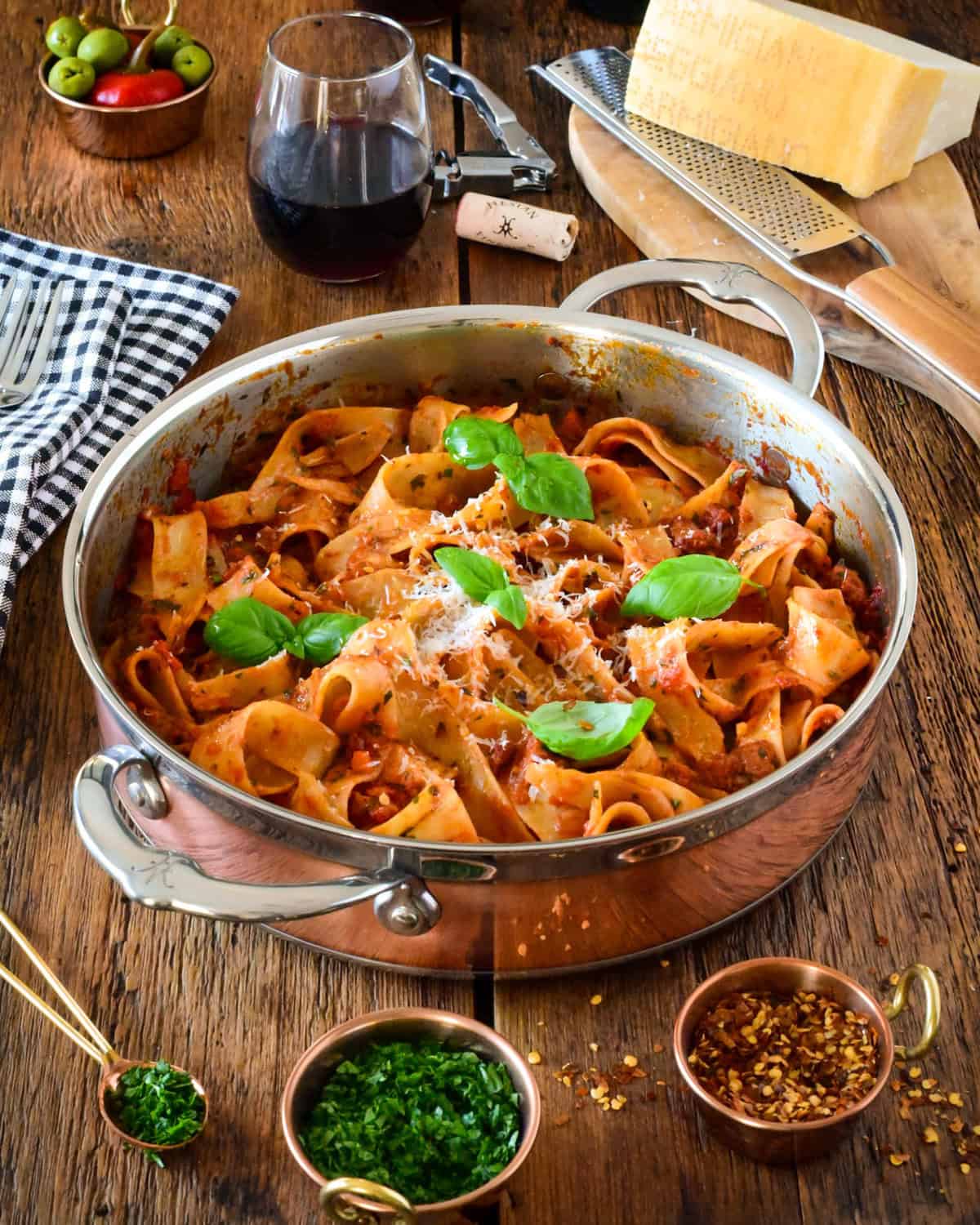 A copper pot of spicy Italian sausage ragu with pappardelle pasta.