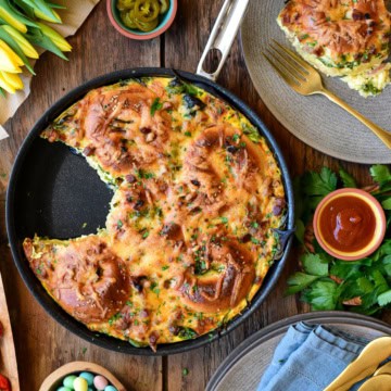 A bagel bake skillet bake with a piece removed and on a plate.