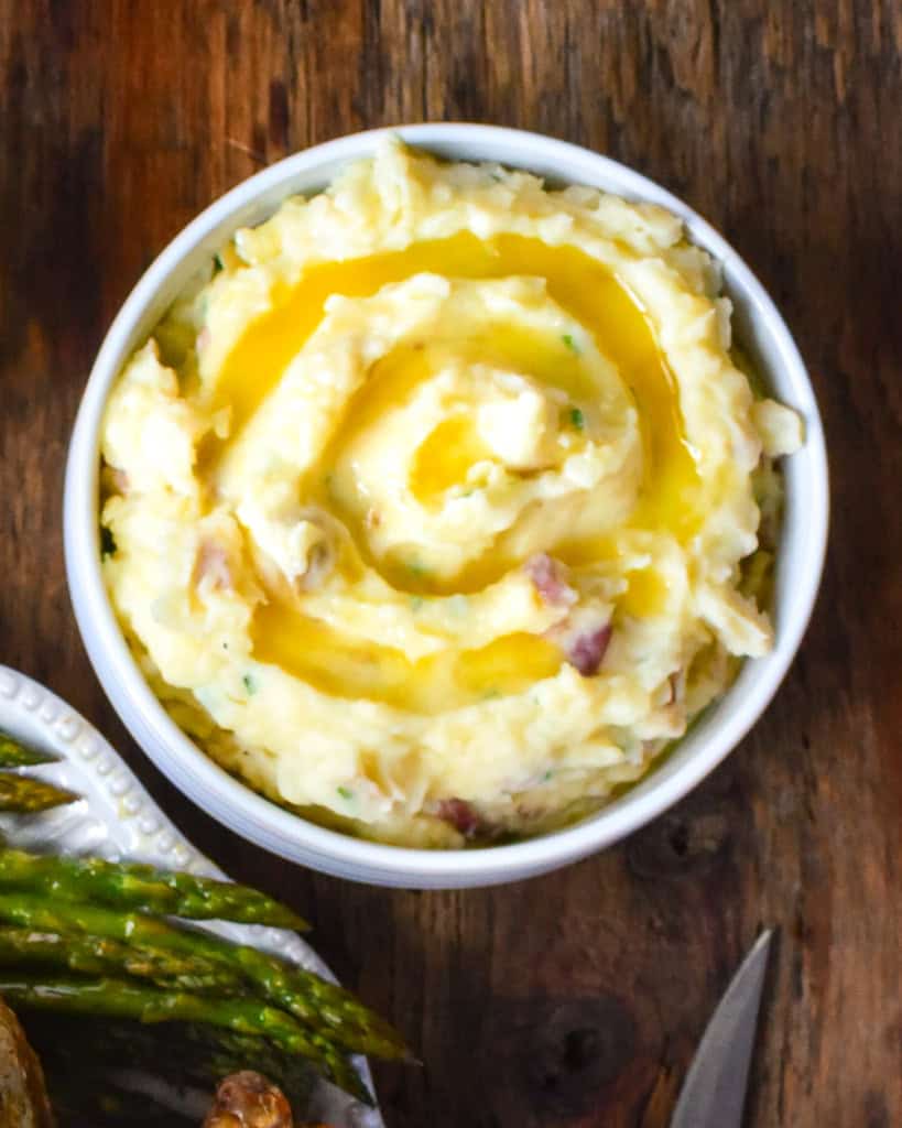 A bowl of mashed potatoes with a swirl of melted butter.