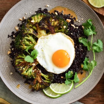 A serving of a stir-fried black rice with broccoli and a fried egg.