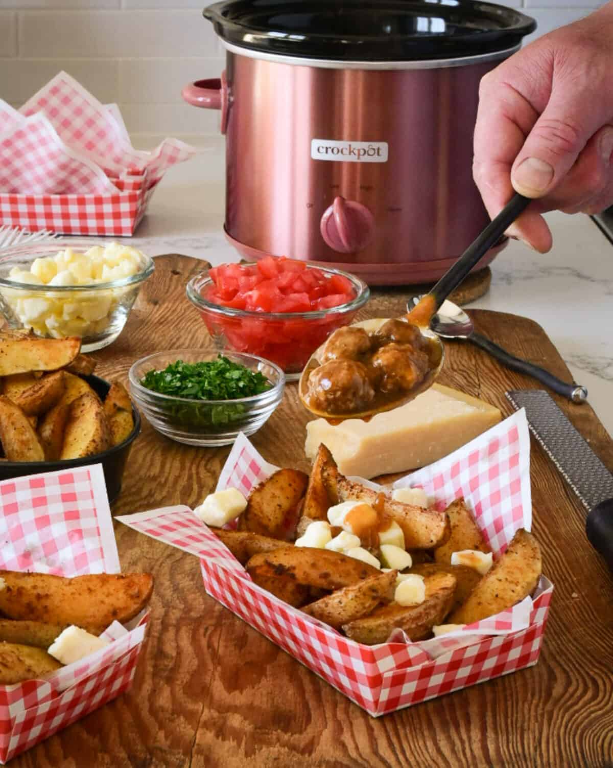 Spooning meatball gravy onto potato wedges and curds.