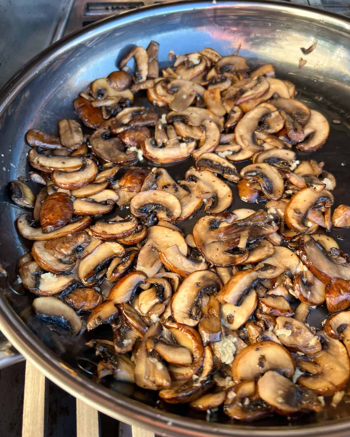 A skillet of sautéed mushrooms on a grill.