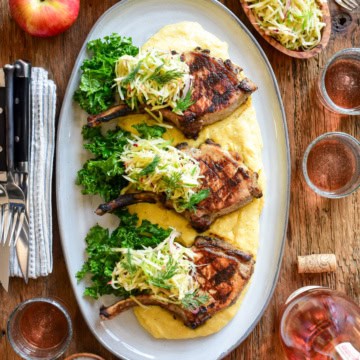 Three pork chops served on polenta with an apple slaw.