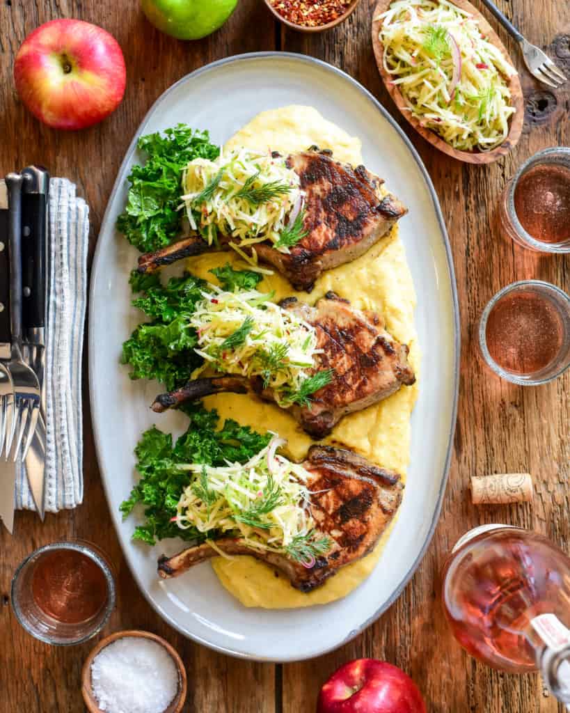 Three pork chops served on polenta with an apple slaw.