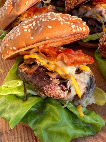 A loaded mushroom, Pancetta and Asiago Burger with lettuce on a sesame seed bun.